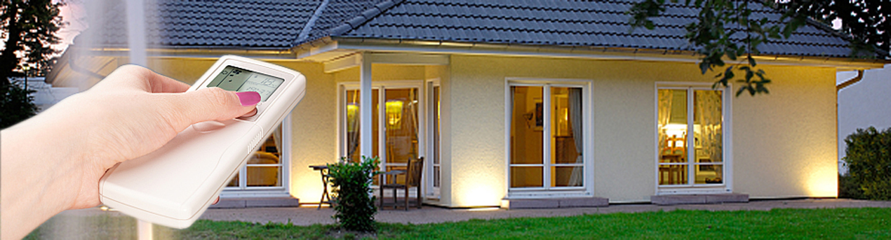 Bedienung einer Hausautomation per Funkfernbedienung vor einem beleuchteten Haus